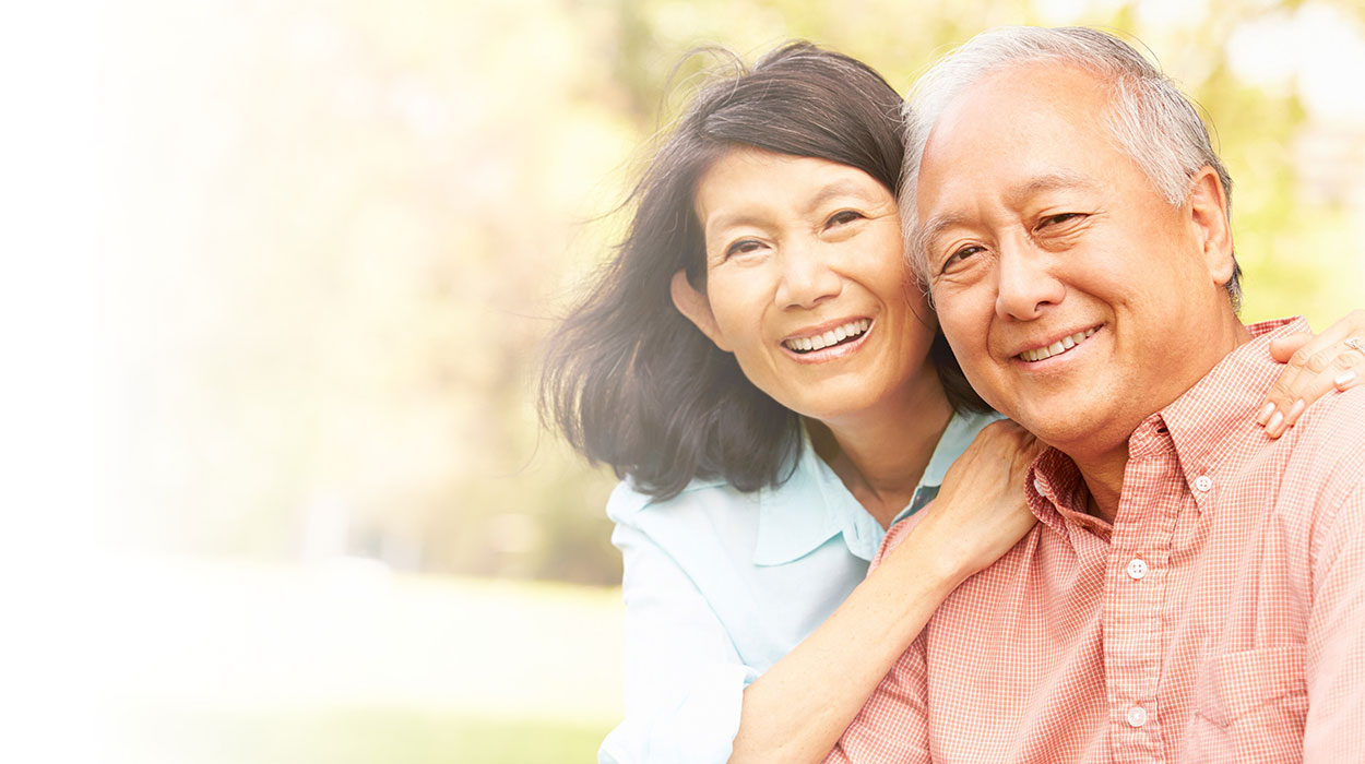 Smiling couple enjoying a sunny day outdoors, embracing warmly.