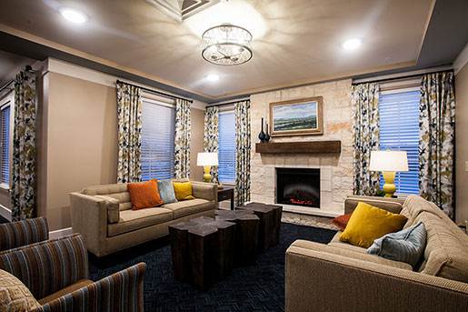 Cozy living room with two sofas, colorful pillows, and a stone fireplace.