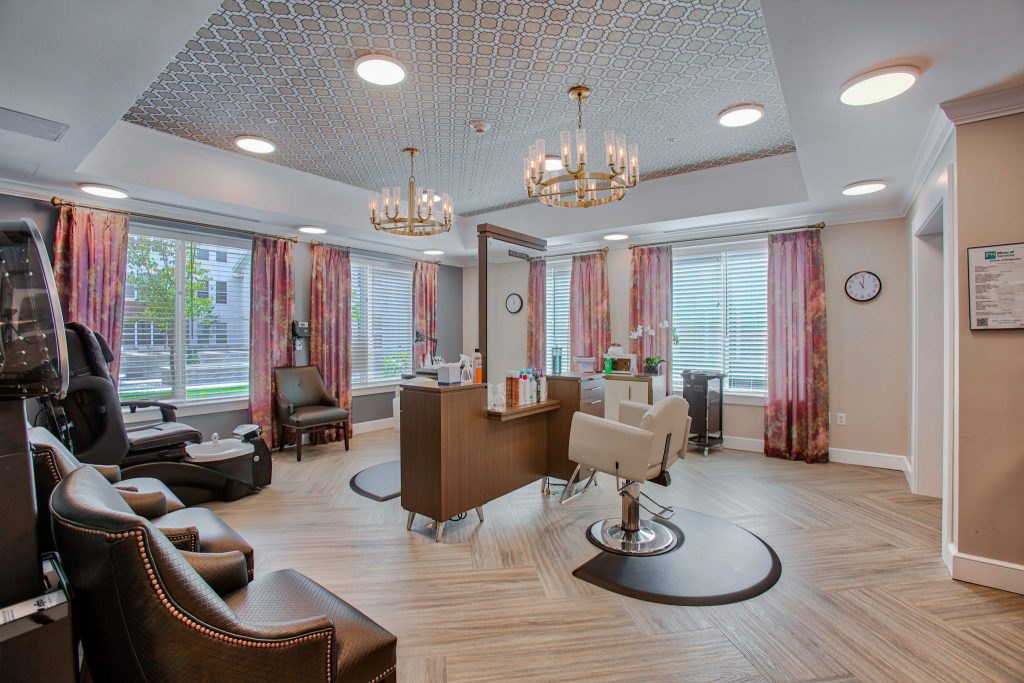 Bright salon area with styling chairs, pink curtains, and elegant chandeliers.
