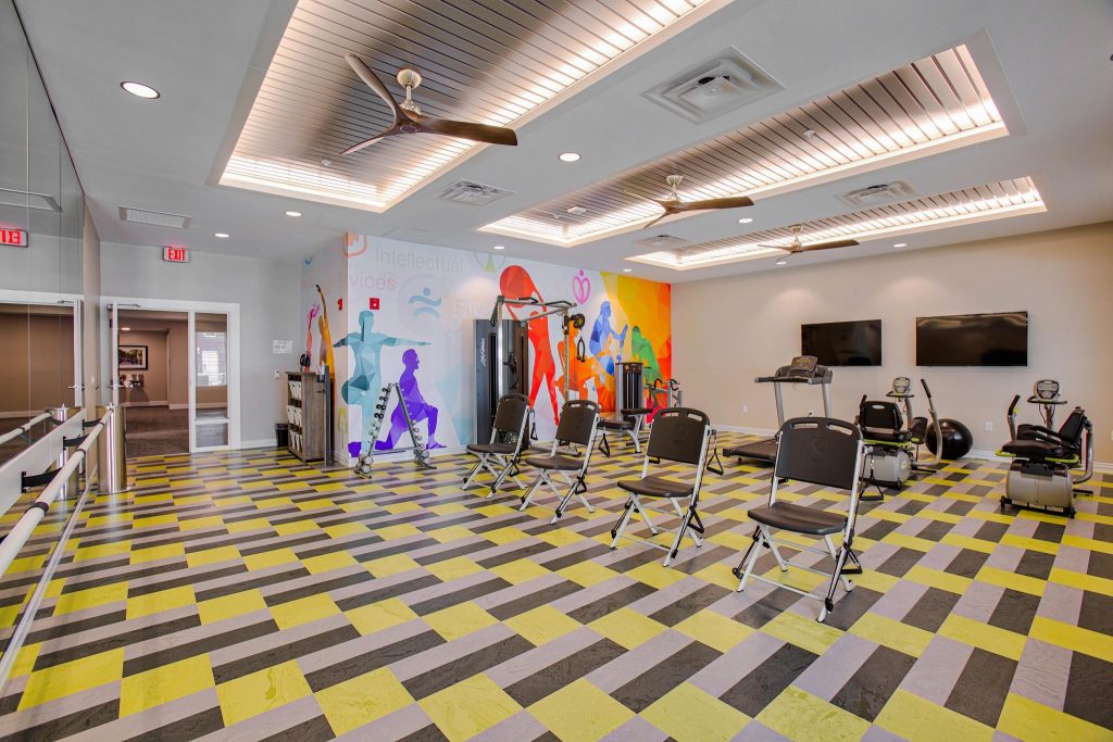 Colorful exercise room with equipment and vibrant wall mural.