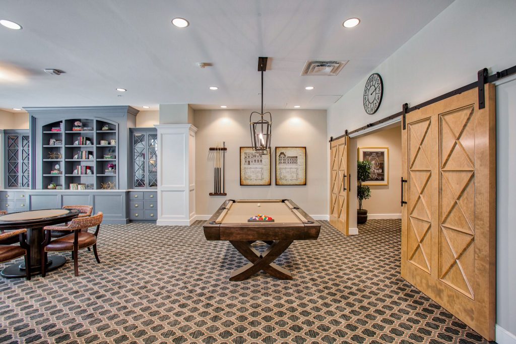 Elegant recreation room with a pool table and built-in bookshelves.