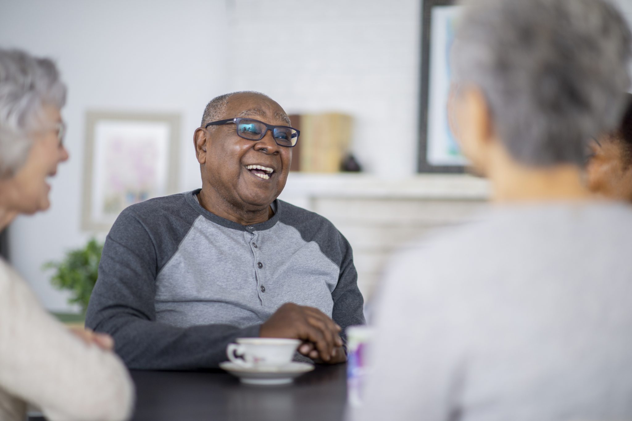 Group of seniors laughing and enjoying coffee together indoors.